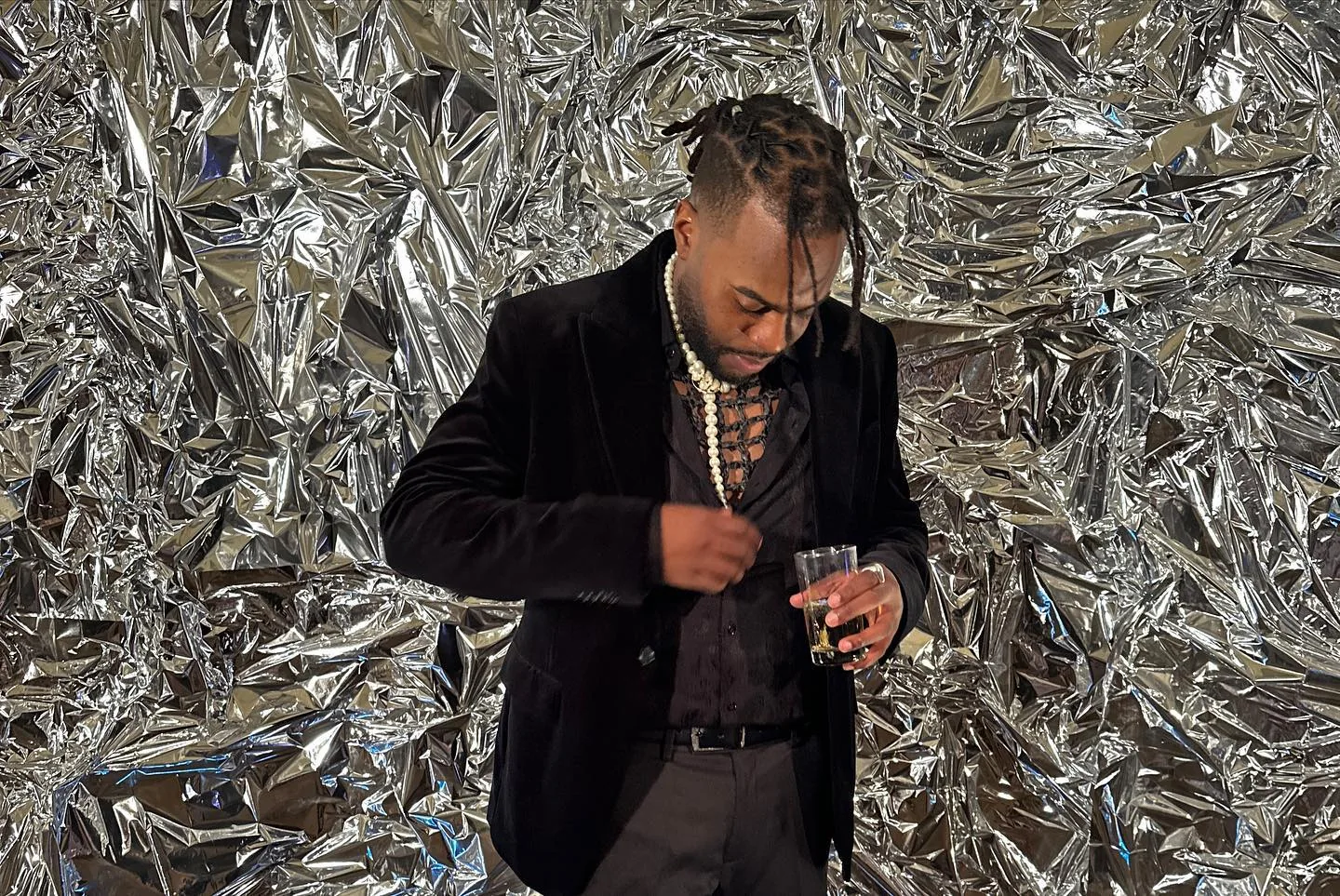Andrew dressed in a black suit in front of a metallic backdrop